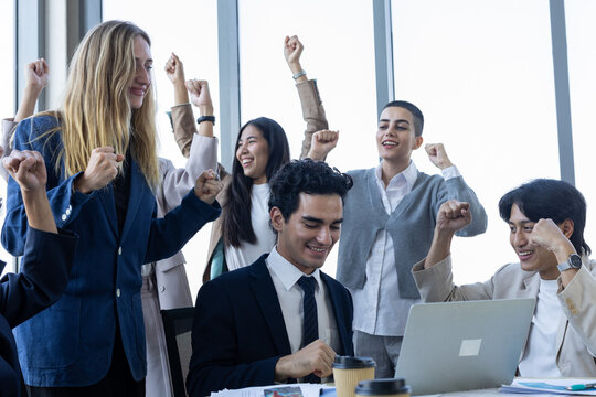 Happy business team celebrating success diverse people cheering raising hands in modern office workplace enjoying achievement
