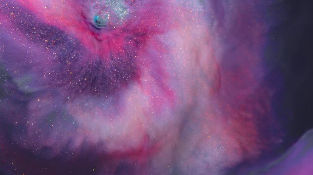 Pink, violet and gold ink clouds billow and twist like a glowing deep space nebula in a macro close-up shot.