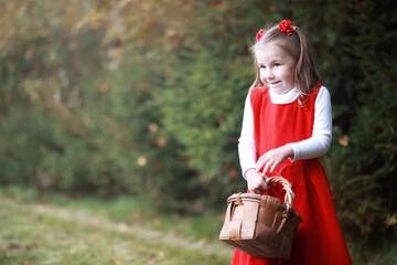 Obraz premium A little girl in a red hat and dresses is walking in the park. Cosplay for the fairytale hero 