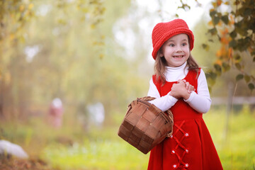 Obraz premium A little girl in a red hat and dresses is walking in the park. Cosplay for the fairytale hero 