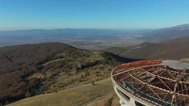 Aerial view flying over the Buzludzha monument in Bulgaria. Majestic and abandoned soviet building on top of a mountain peak in autumn