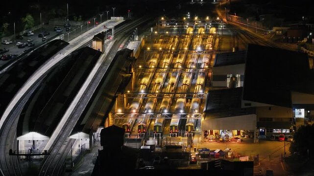 Aerial night view of Salisbury Traincare Depot showing multiple passenger trains parked beneath bright depot lighting beside railway tracks and station infrastructure