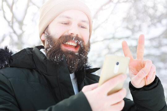 Outdoor portrait of handsome man in coat and scurf. Bearded man in the winter woods.