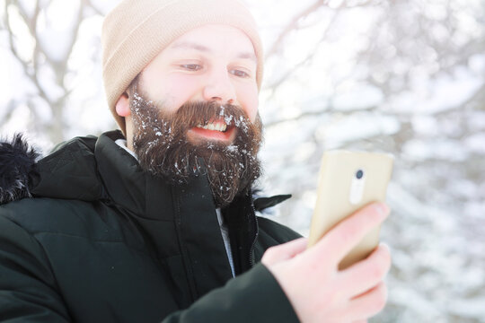 Outdoor portrait of handsome man in coat and scurf. Bearded man in the winter woods.