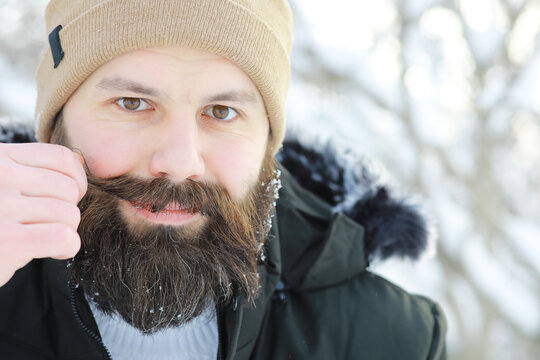 Bearded man in the winter woods. Attractive happy young man with beard walk in the park.