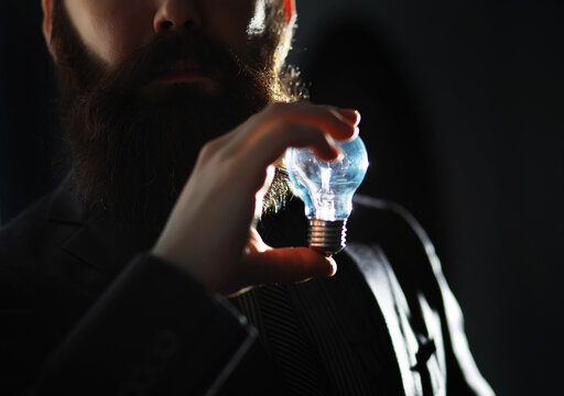 A bearded man in a suit holds an object in his hand. Concept of time and ideas. Aspiration and development.