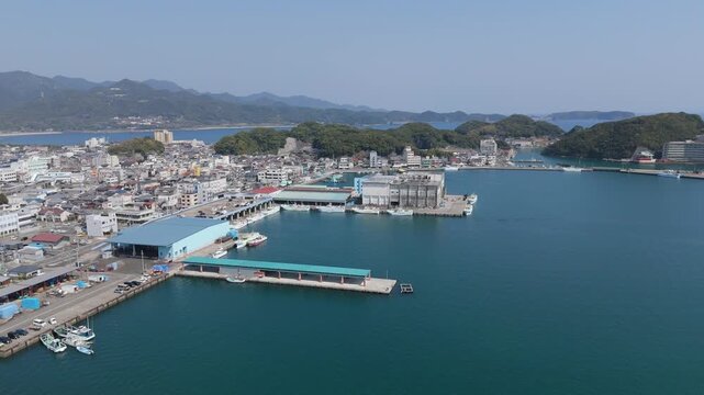 Aerial drone footage showing a high angle view of a regional tuna market wholesale building and harbor dock facilities. Captures the commercial fishing trade infrastructure highlighting themes of glob