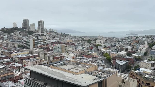 A view of San Francisco&rsquo;s North Beach district, capturing dense urban architecture, residential rooftops, and bay waters beyond under soft overcast daylight.