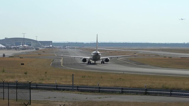 Airplane taxiing on runway during daytime with another plane in distance.