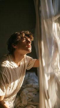 Golden Hour Serenity: A young man with curly hair bathed in the warm, soft light of the golden hour, looking upwards with his eyes closed.