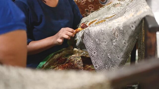 A Person Creating Traditional Batik by Hand on FabricA Person Creating Traditional Batik by Hand on Fabric