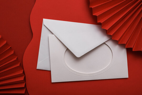 Chinese New Year background. White envelope and Asian traditional paper fans and wavy red layers. Creative layout.