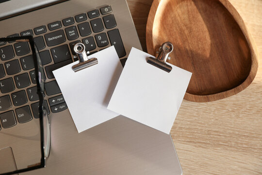 Laptop, blank cards with clips, tray on table. Natural sunlight. Business concept. Top view