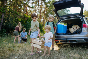 Obraz premium Family unloading luggage from car and setting up a campsite.