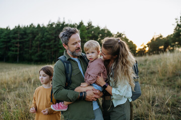 Obraz premium Family hiking together through countryside during summer camping trip.