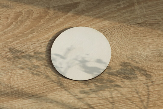 Round white coaster on table with natural sunlight