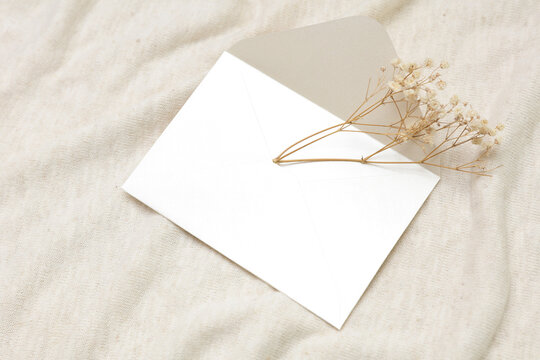 White blank invitation card with dry grass on fabric background
