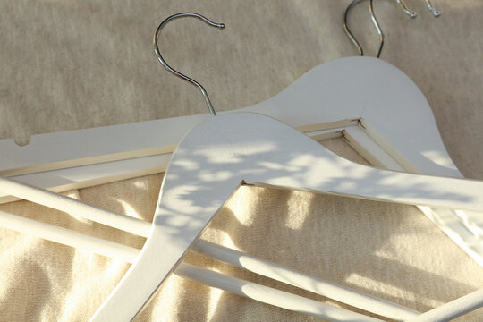 White hangers on a fabric background with sunlight. Fashion, shopping concept.