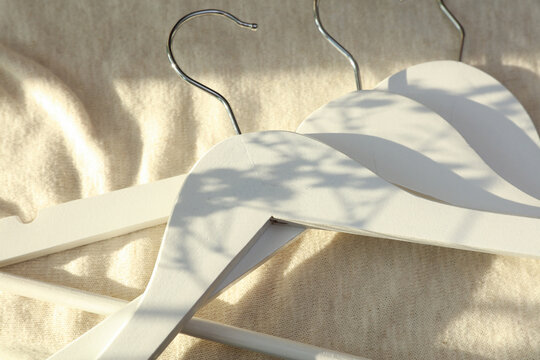 White hangers on a fabric background with sunlight. Fashion, shopping concept.