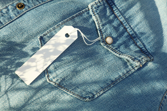 White blank tag on the pocket of a blue denim shirt with sunlight