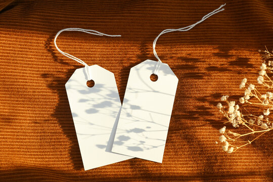 White blank tags on orange corduroy background with natural sunlight