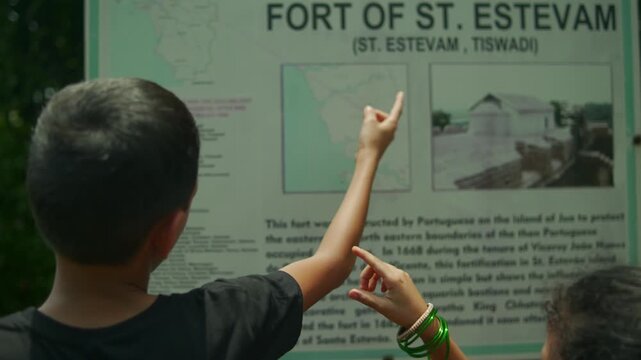 Children point at a map and read an information board at St Estevam Fort. A curious sightseeing moment for educational travel, local history and childhood learning content.