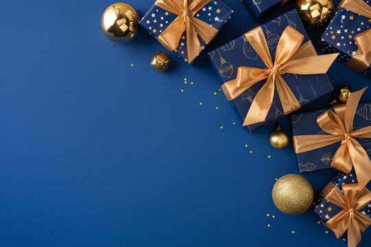 Blue and gold Christmas gifts with satin ribbons and ornaments for Merry Christmas and Happy New Year celebration on festive dark blue copyspace
