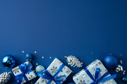 Blue Christmas gifts and ornaments with ribbons and snowflake decorations for holiday greeting on dark blue template