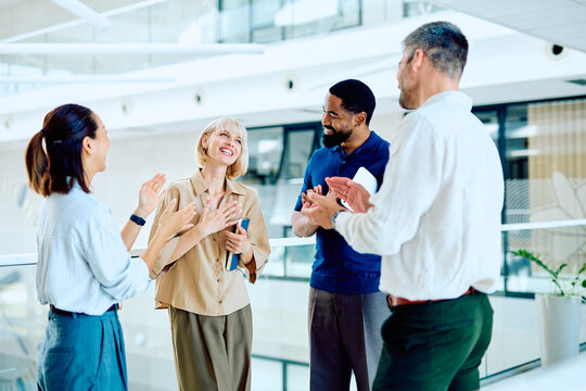 Diverse business team clapping, celebrating success and showing support in a modern office environment