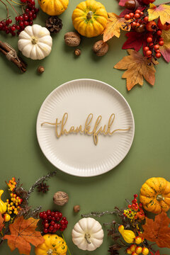 Thankful plate with pumpkins, autumn leaves and harvest decorations for Thanksgiving dinner with plate on green table