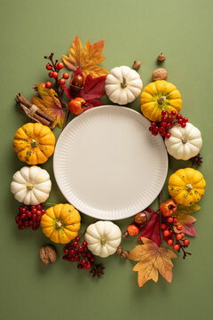 Autumn Thanksgiving vertical arrangement with pumpkin, fall leaf and empty plate for seasonal serving on green beautiful table