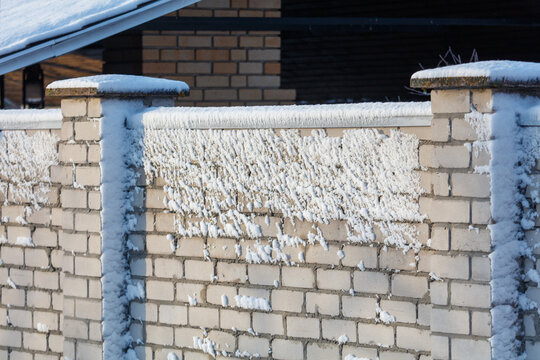 Frost clings to a light-colored brick wall