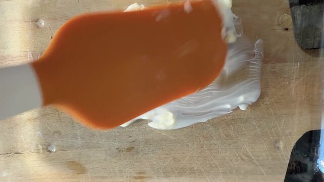 Spatula spreading the butter on casserole dish