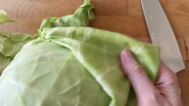 Hands Shredding Fresh Cabbage on a Wooden Cutting Board
