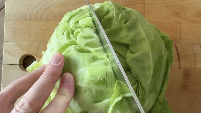 Knife Halving a Whole Cabbage on a Wooden Board