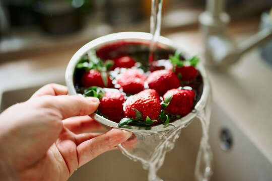 POV close up washing fresh strawberries in kitchen sink