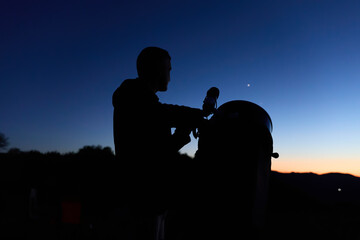 Amateur astronomer observing stars, planets, Moon and other celestial objects with a telescope in nature. © astrosystem