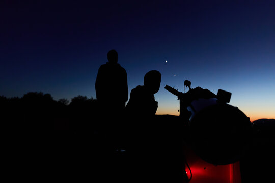 Amateur astronomers observing stars, planets, Moon and other celestial objects with a telescope in nature.