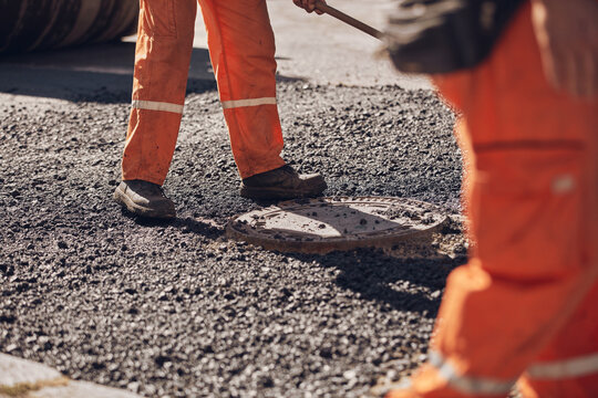 Construction worker working on a new asphalt layer on a public street.