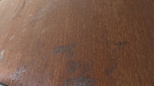 Horizontal close up view of a weathered corten steel wall panel with a rusted metal texture