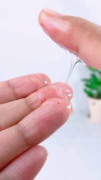 Showing sticky gel liquid on fingertip. Clear adhesive or thick gel texture on hand. Skincare or cosmetic product viscosity concept.