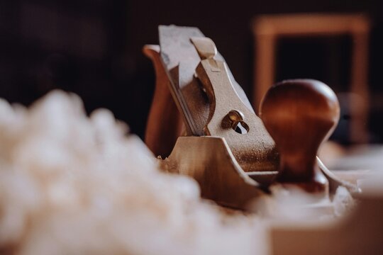 Close up of vintage wooden hand plane tool on a workbench with wood shavings in a carpentry workshop