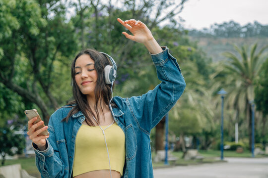 Young woman listening music while walking in the street. Travel, tourism, technology, blogging concept