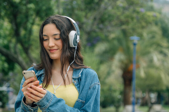 Young woman listening music while walking in the street. Travel, tourism, technology, blogging concept