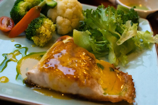 A Delicious Platter of Fish Fillet with Colorful Vegetables Including Broccoli, Cauliflower, and Fresh Greens, Drizzled with a Flavorful Sauce