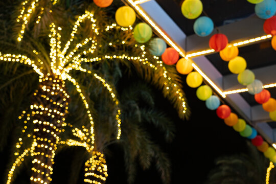 Brightly Illuminated Tropical Scene Featuring Colorful Lanterns and Twinkling Lights on Palm Trees Against a Night Sky