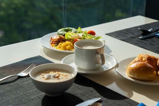 A Beautifully Arranged Breakfast Featuring Savory Dishes, Fresh Salads, and Warm Bread in a Sunlit Dining Setting