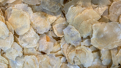 Close-up overhead view of dried, delicate, pale yellow flakes, perhaps fish scales or dried petals, filling the frame © Sobirin