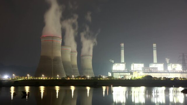 night view of thermal power plant cooling towers emitting steam