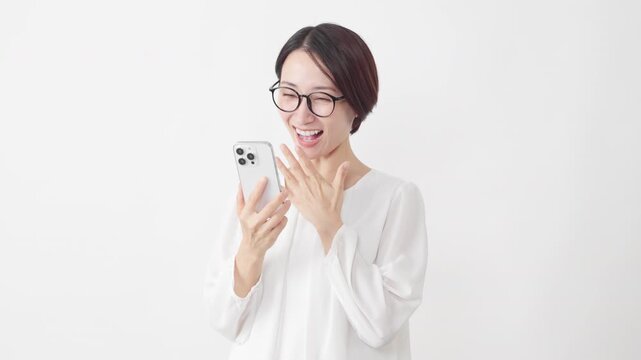 スマートフォンを使うメガネをかけたカットソー姿の女性　ライフスタイルイメージ	